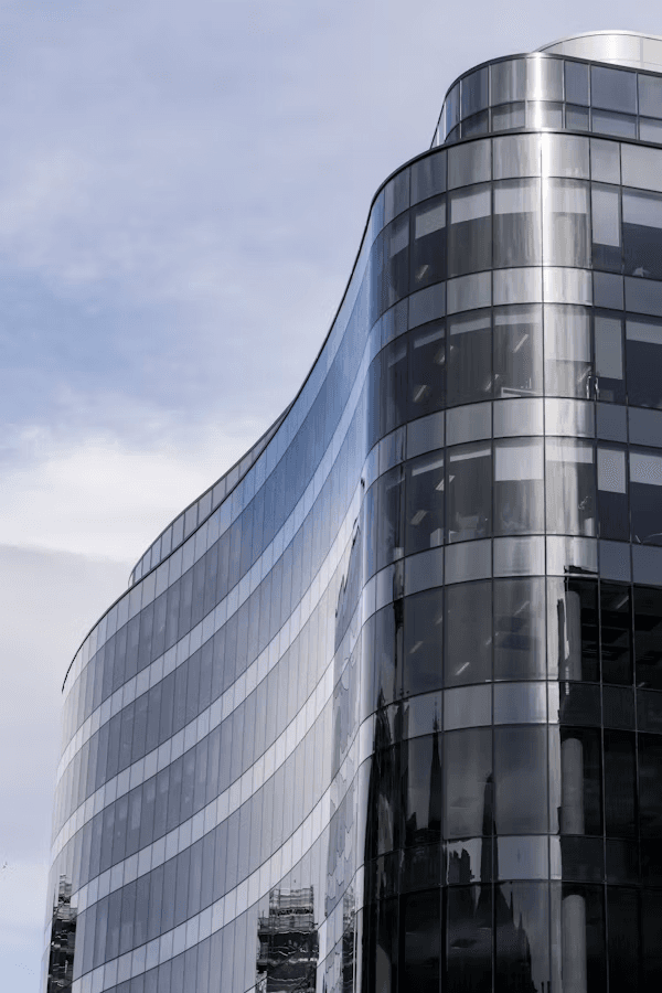 Curved glass office facade against a pale sky.
