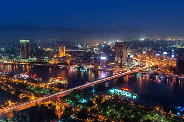 Cairo at night from above, with the Nile, lit bridges and the city skyline.